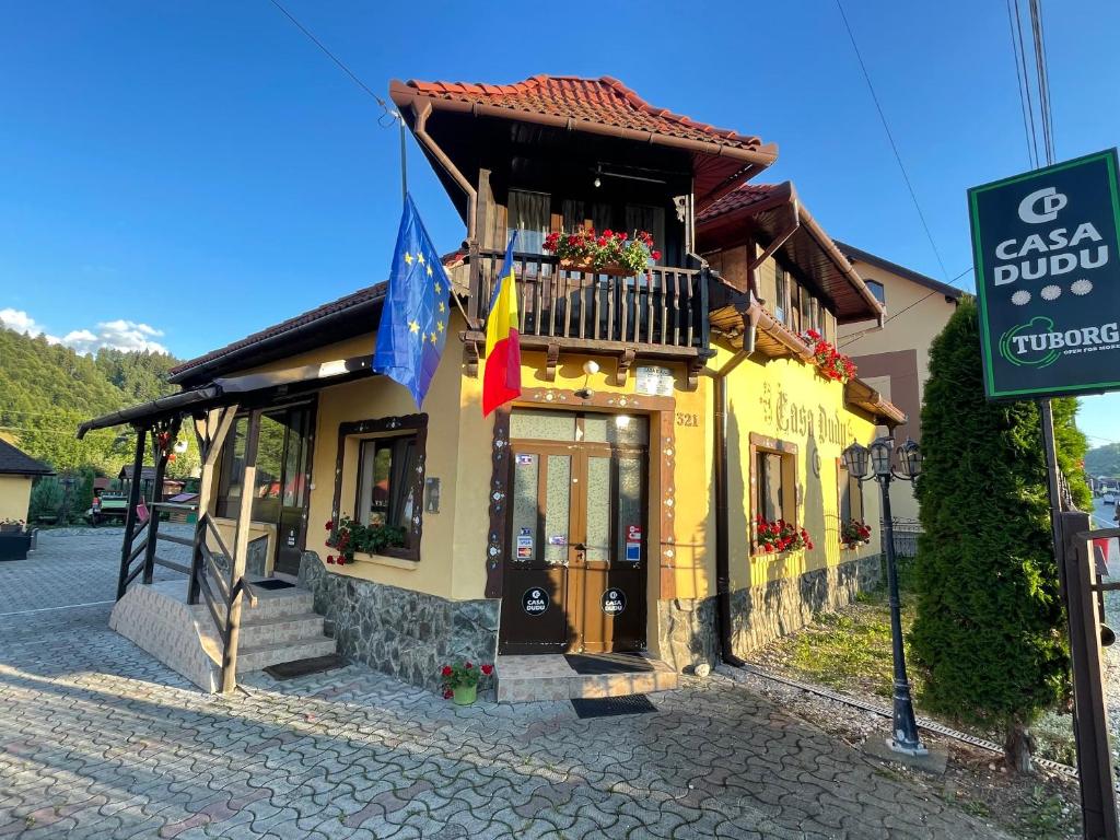 een geel gebouw met een balkon en vlaggen erop bij Casa Dudu in Moieciu de Jos