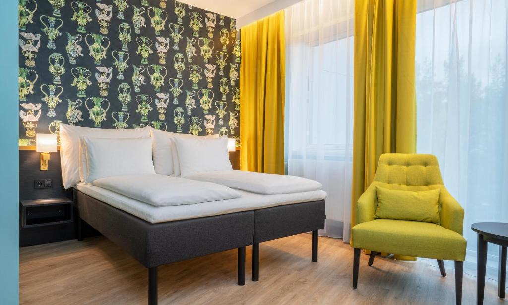 a bedroom with a bed and a yellow chair at Thon Hotel Linne in Oslo