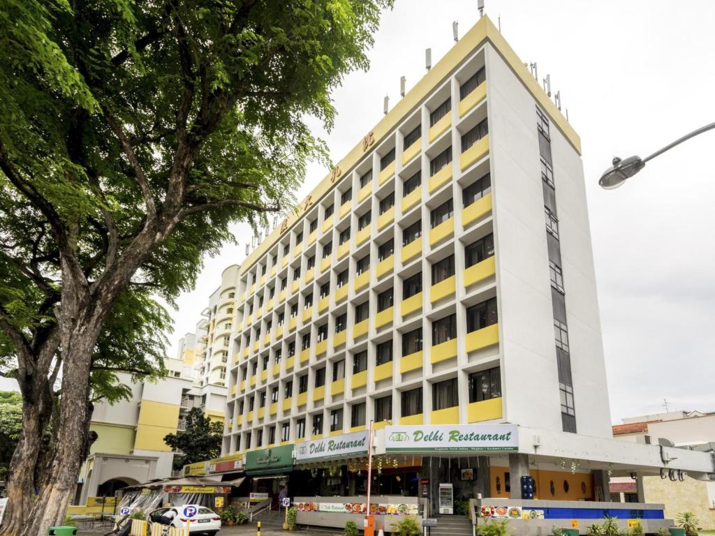 a large white building with yellow accents at L Hotel at Broadway in Singapore