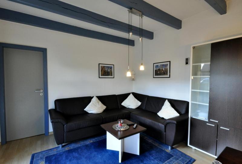 ein Wohnzimmer mit einem schwarzen Sofa und einem Tisch in der Unterkunft Huus vör d Diek Wohnung 1 in Neuharlingersiel