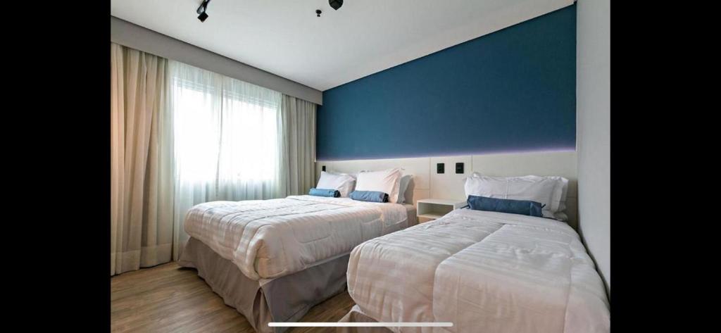 um quarto de hotel com duas camas e uma parede azul em *2112Apartamento top com garagem na vila olimpia em São Paulo