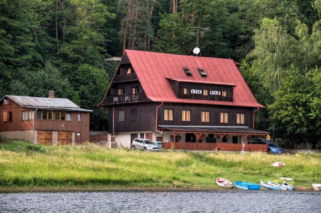 une grande maison avec un toit rouge à côté d'un lac dans l'établissement Chata Lucka, à Bítov
