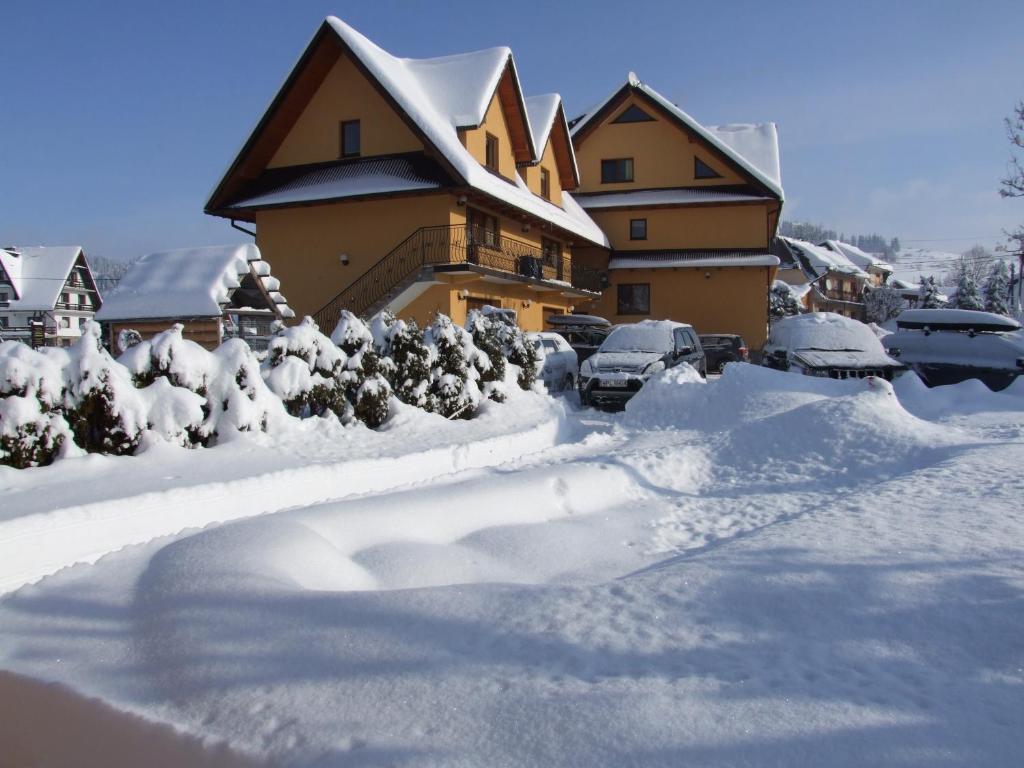 una casa cubierta de nieve con coches aparcados en ella en Wynajem Pokoi ,,Góry Tatry Wypoczynek "Paweł Kuczyński, en Czarna Góra