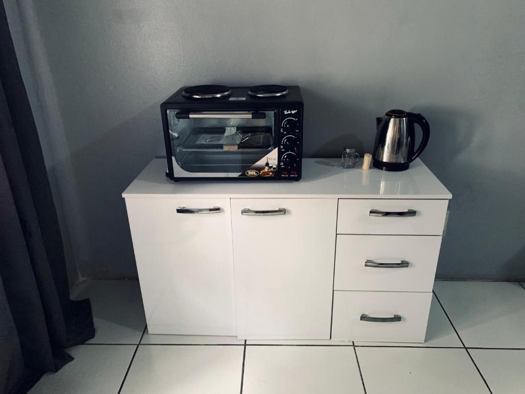 a microwave sitting on top of a white cabinet at The Eden Lodge Verulam in Verulam