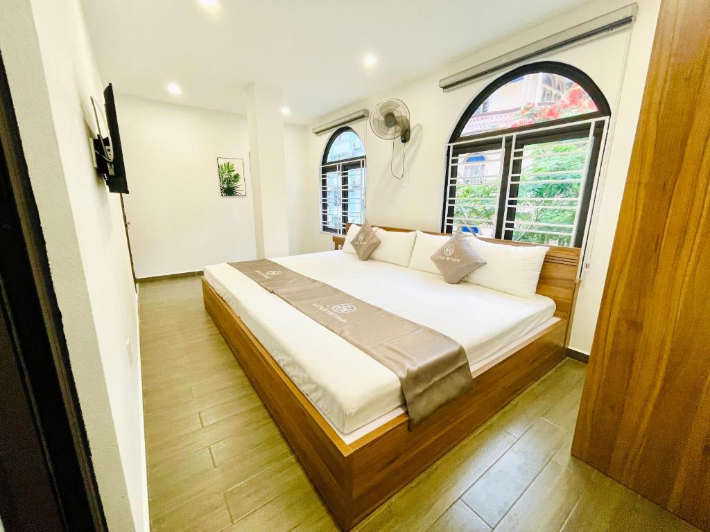 sypialnia z dużym łóżkiem i 2 oknami w obiekcie Little Vietnam Hotel - Cát Bà w mieście Cát Bà