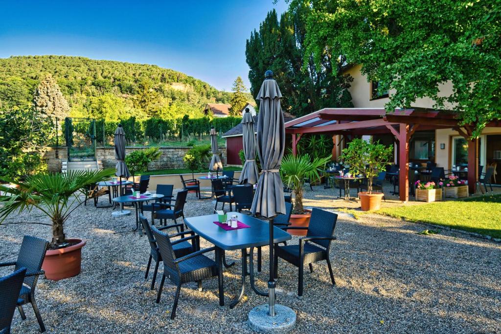 a group of tables and chairs with an umbrella at Hotel Tenner in Neustadt an der Weinstraße