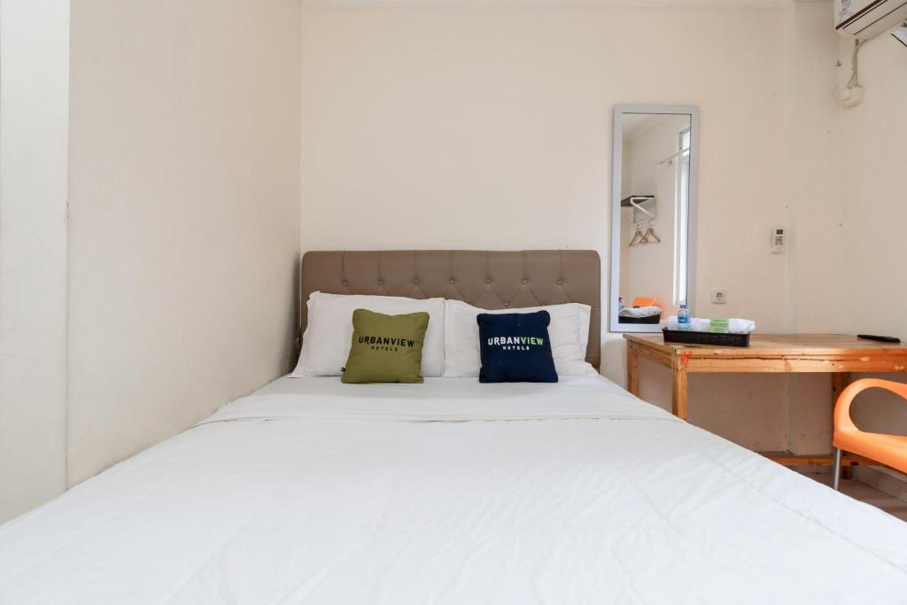 une chambre avec un lit blanc avec deux oreillers dessus dans l'établissement Urbanview Hotel Minongga Pondok Labu by RedDoorz, à Jakarta