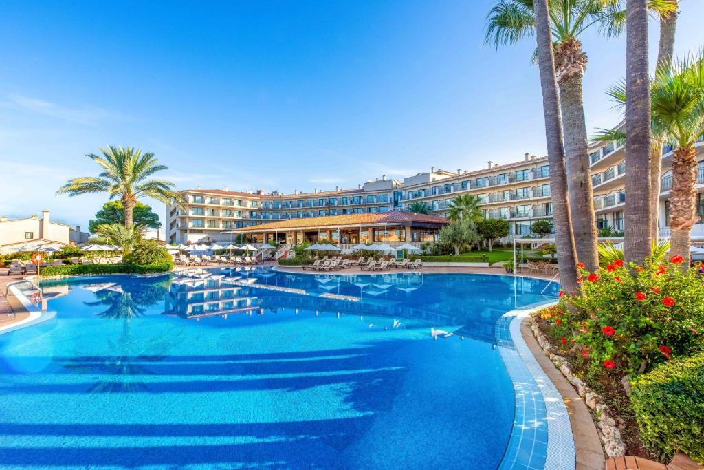 a large swimming pool with a hotel in the background at Valentin Son Bou in Son Bou