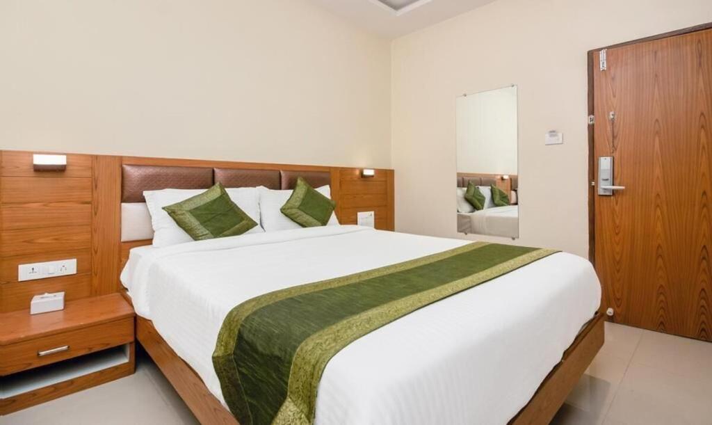 a bedroom with a large white bed with a wooden headboard at Hotel Volga Plaza in Mumbai