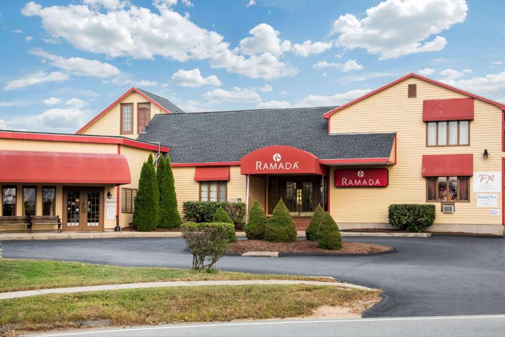 a store front of a building with red awnings at Ramada by Wyndham Groton in Groton