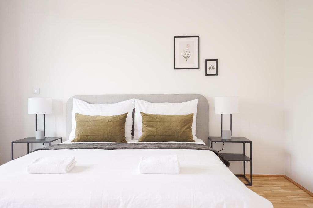 1 dormitorio blanco con 1 cama blanca grande y 2 lámparas en Green Garden Apartment w/.Balcony near Thermal Spa, en Viena