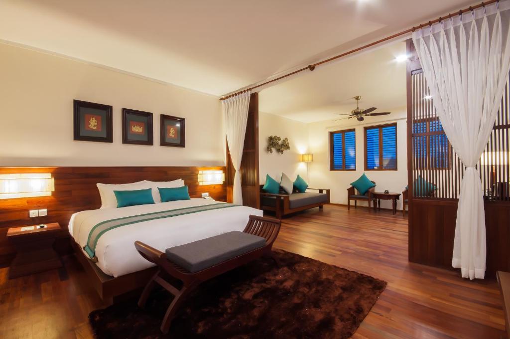 a bedroom with a bed and a chair in a room at Lotus Blanc Resort in Siem Reap