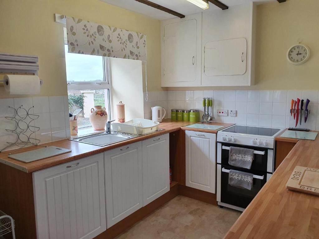 a kitchen with white cabinets and a sink and a stove at Crailloch Croft Cottages in Stranraer