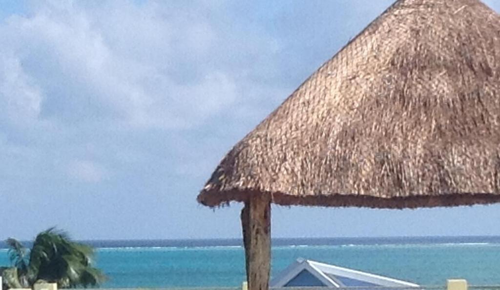 einen Strohschirm am Strand in der Nähe des Ozeans in der Unterkunft Caribbean Sunrise Cottage in Caye Caulker