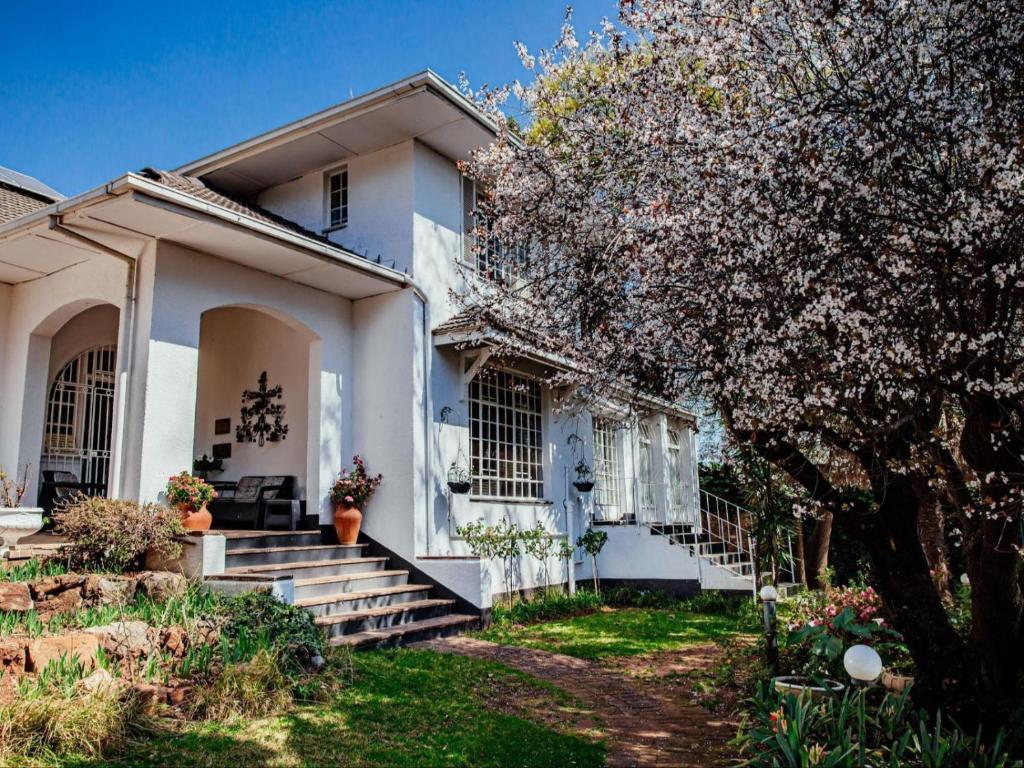 una casa bianca con scale e un albero di Twickenham Guest House a Johannesburg
