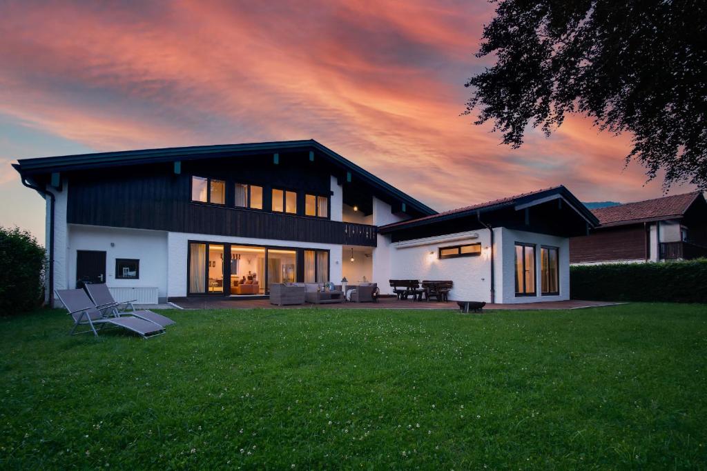 una casa con césped frente a una puesta de sol en Ferienhaus Seehof mit Sauna & offenem Kamin en Schliersee