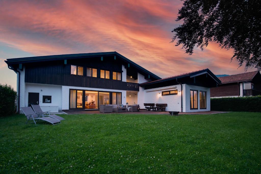 a house with a lawn in front of a sunset at Ferienhaus Seehof mit Sauna & offenem Kamin in Schliersee