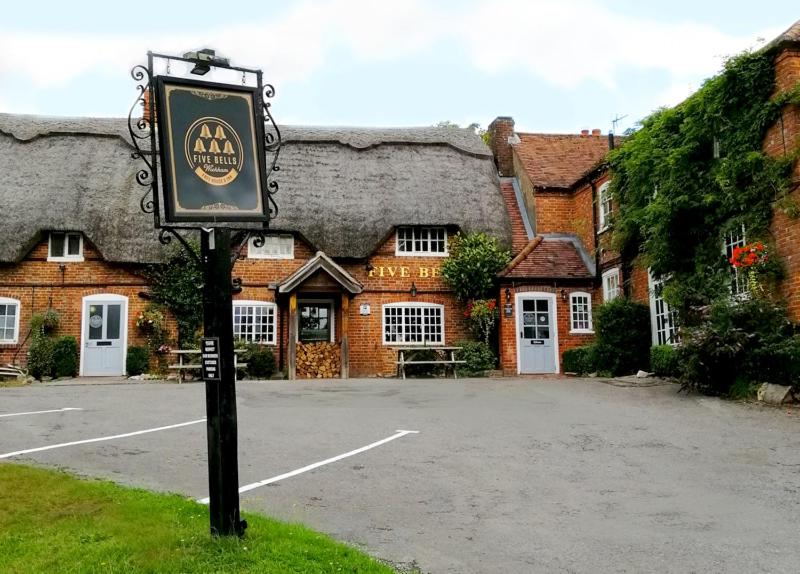 un cartel en el césped frente a un edificio en Five Bells Wickham en Newbury