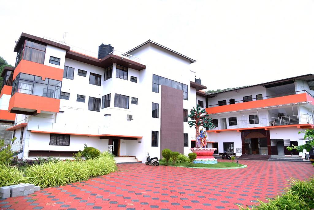 a large white building with a red brick driveway at NIRVANA HOLISTIC LIVING in Varagampadi