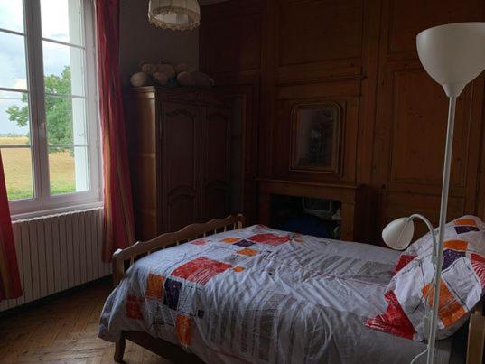 Un dormitorio con una cama y una lámpara. en chambre chez l'habitant 2, en Biville-la-Baignarde