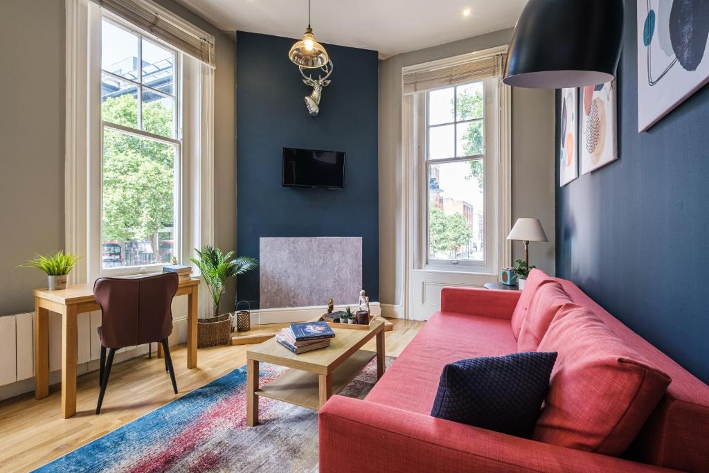 a living room with a red couch and a tv at Sunny Corner Apartment in Center of London (1) in London