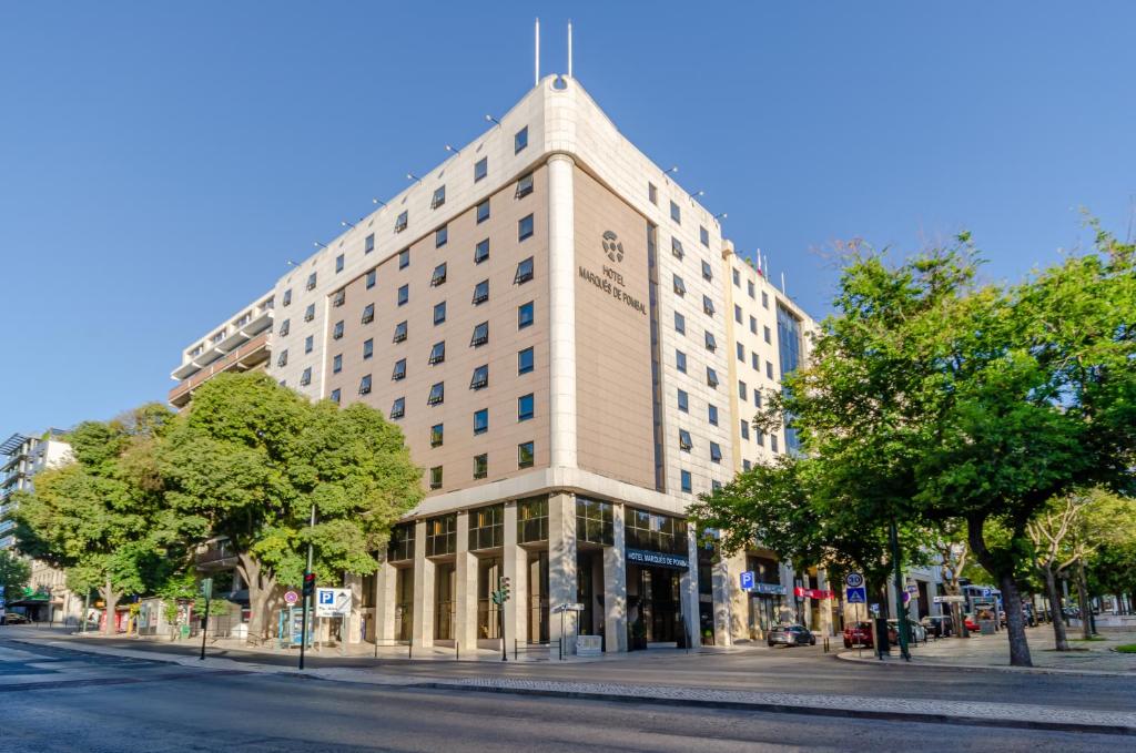 een groot gebouw aan een stadsstraat met bomen bij Hotel Marques De Pombal in Lissabon