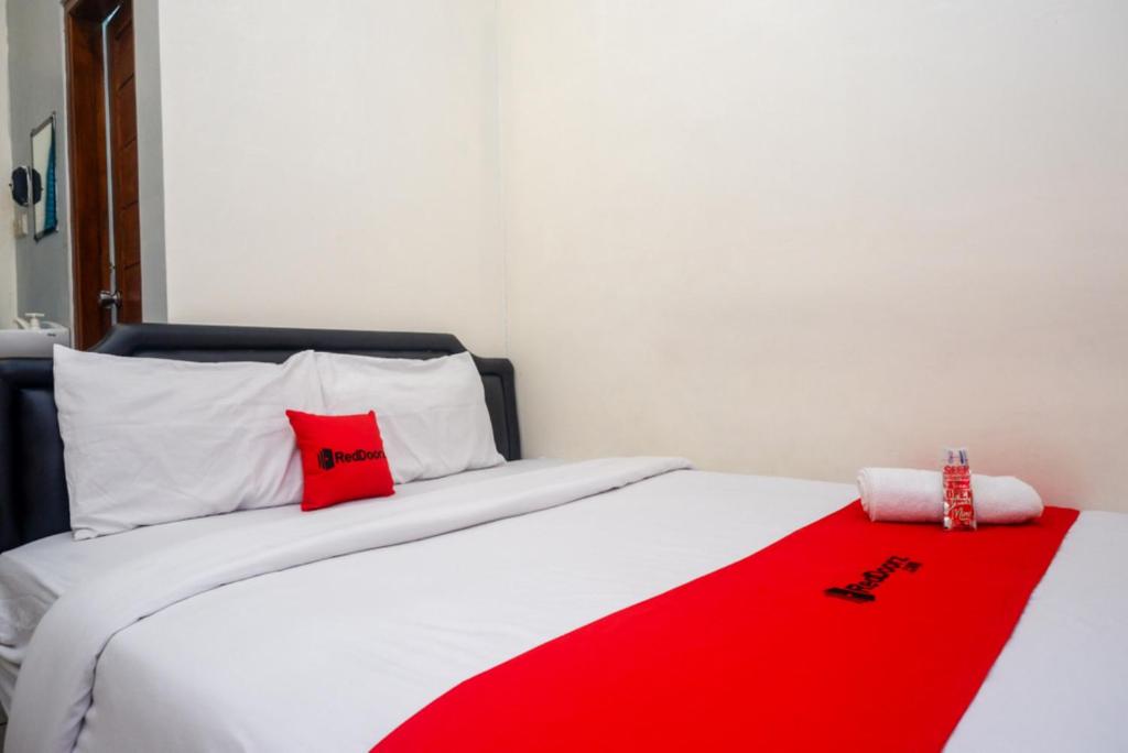 - une chambre avec une couverture rouge sur un lit dans l'établissement ReDdoorz At Mahameru Residence Yogyakarta, à Yogyakarta