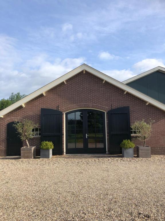 a brick building with glass doors and potted plants at Gastenverblijf op de Prins Hendrik Hoeve in Buren in Buren