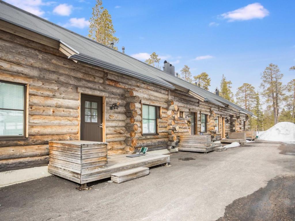 una cabaña de madera con bancos fuera de ella en Holiday Home Maahisenrinne 1 as 4 by Interhome en Äkäslompolo