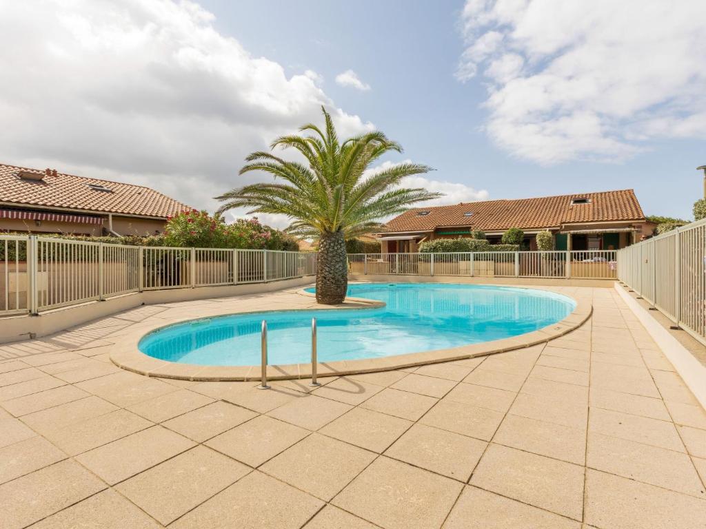 a swimming pool with a palm tree in a yard at Holiday Home Plage sud-3 by Interhome in Capbreton
