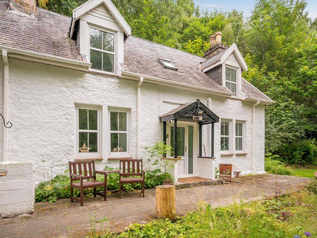 a white house with two chairs and a table at Holiday Home Dancot by Interhome in Invermoriston