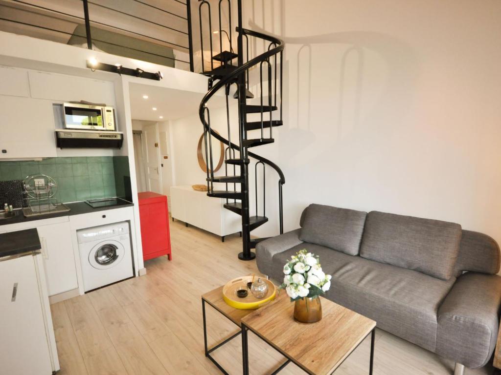 a living room with a couch and a spiral staircase at Apartment Les Jardins d&#39;Amaryllis-8 in Cavalaire-sur-Mer