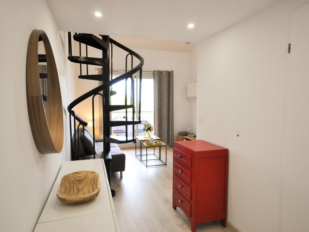 a living room with a red dresser and a spiral staircase at Apartment Les Jardins d&#39;Amaryllis-8 in Cavalaire-sur-Mer