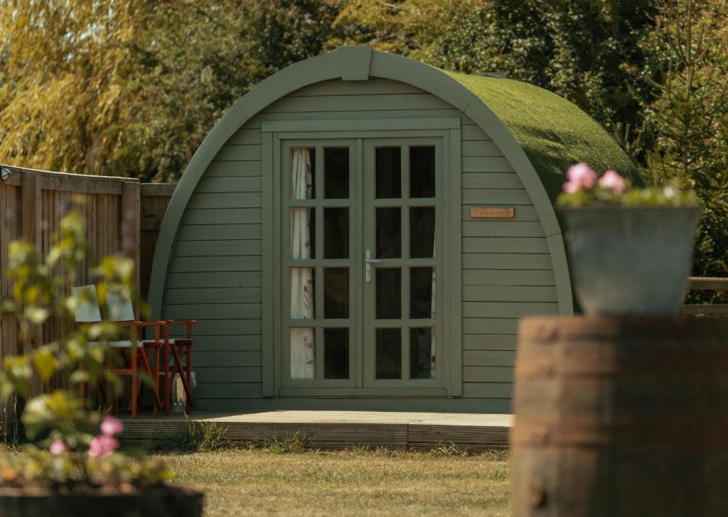 a green shed with a window in a yard at Glamping in Wiltshire the Green Knoll is a charm in Chippenham