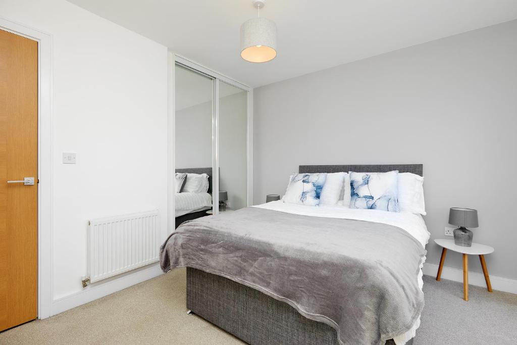 um quarto branco com uma cama grande e almofadas azuis em Royal Derby Hospital Luxury House em Derby