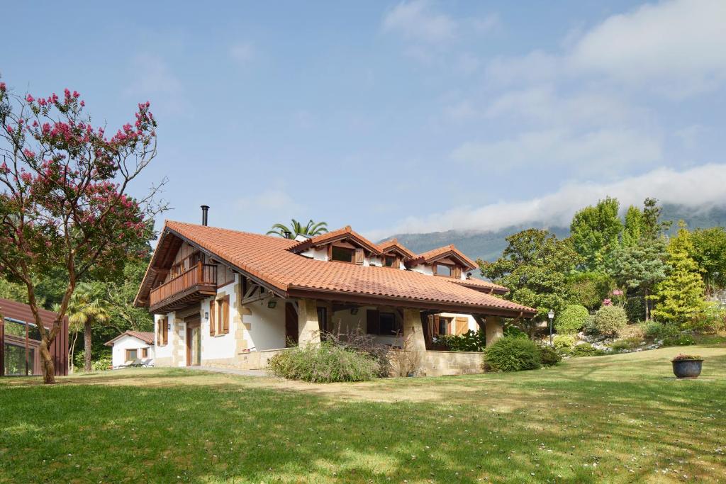 una casa con techo rojo en un patio verde en Villa Jaizubia Golf by FeelFree Rentals, en Hondarribia