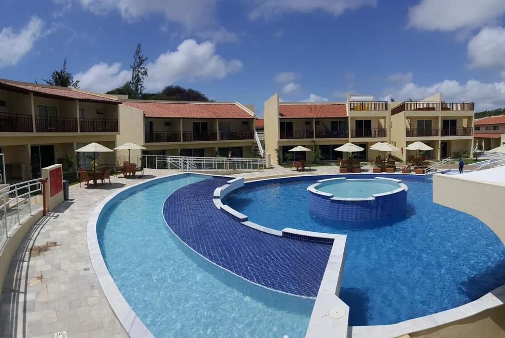 a pool at a resort with tables and umbrellas at Solar Águas Pipa Prime in Pipa