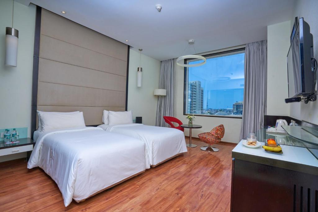 Habitación de hotel con cama blanca grande y escritorio. en E Hotel en Chennai