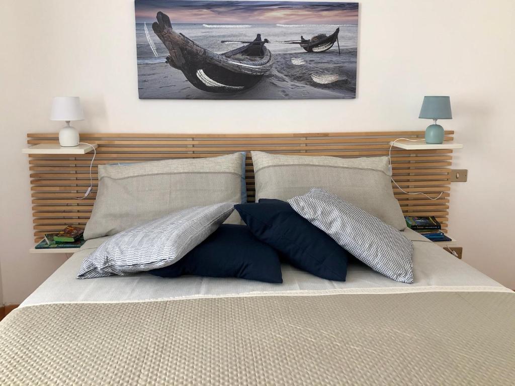 ein Bett mit zwei Kissen und einem Gemälde an der Wand in der Unterkunft Ankon Apartment Palazzo Mazzini in Ancona
