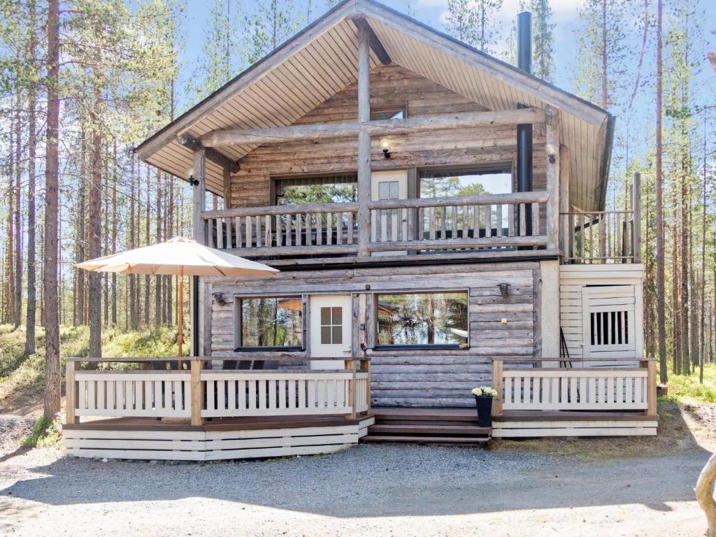 a cabin in the woods with an umbrella at Holiday Home Uuttuniemi by Interhome in Kuusamo