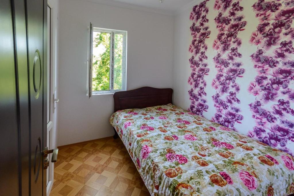 a bedroom with a bed with a floral bedspread and a window at Hotel Kharabadze in Kutaisi
