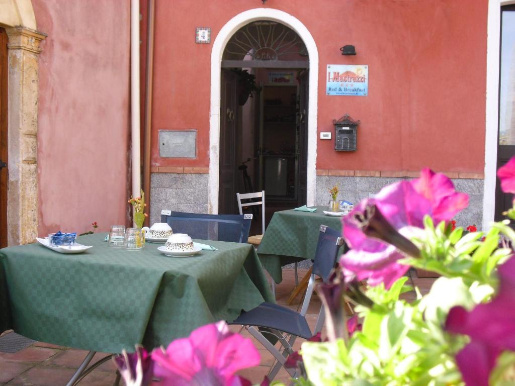 una mesa y sillas frente a un edificio con flores rosas en B&B I Mastrazzi Riposto Giarre, en Riposto