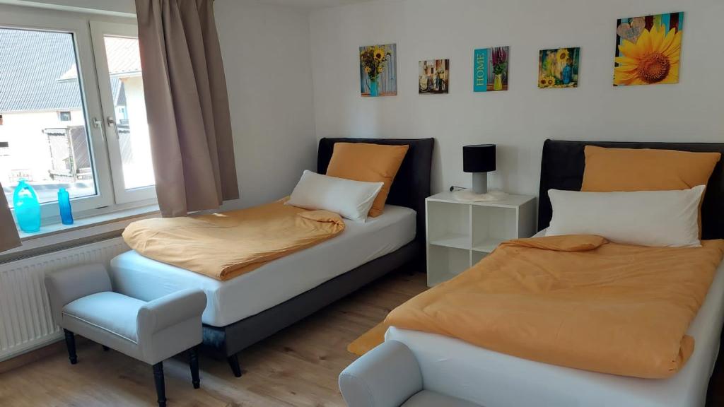 a bedroom with two beds and a chair and a window at Haus Emmerblick in Schieder-Schwalenberg