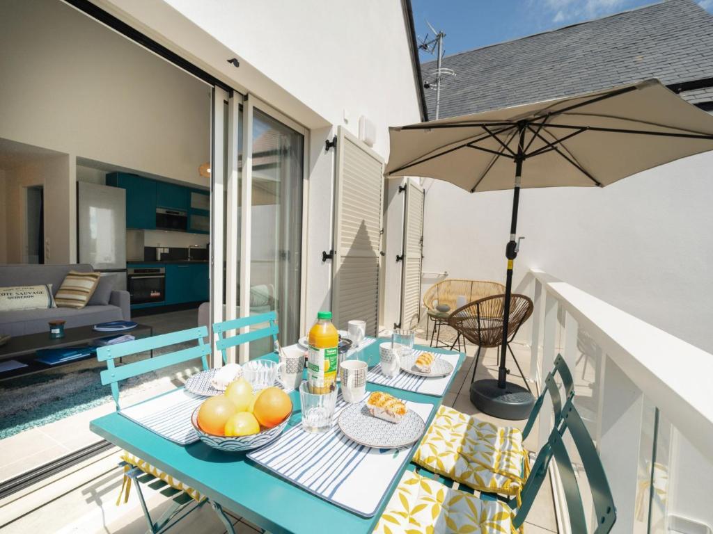 a table with food and an umbrella on a balcony at Apartment Le Clos Moguer-1 by Interhome in Quiberon