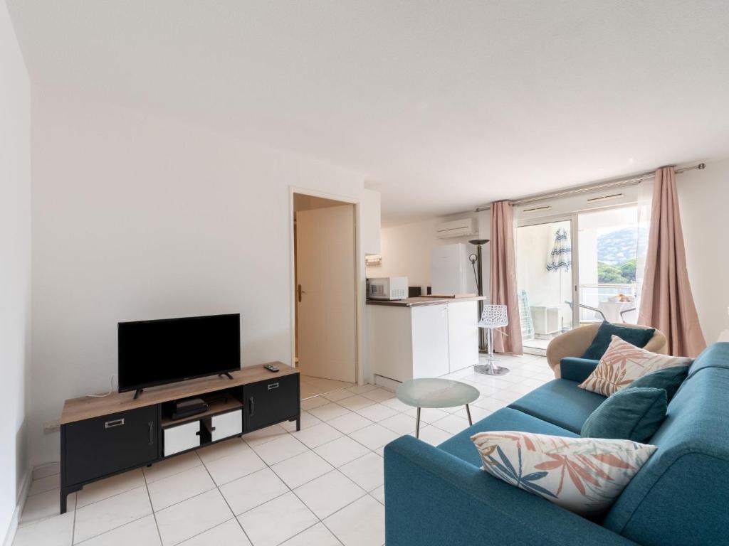 a living room with a blue couch and a tv at Apartment Turquoise-10 by Interhome in Cavalaire-sur-Mer