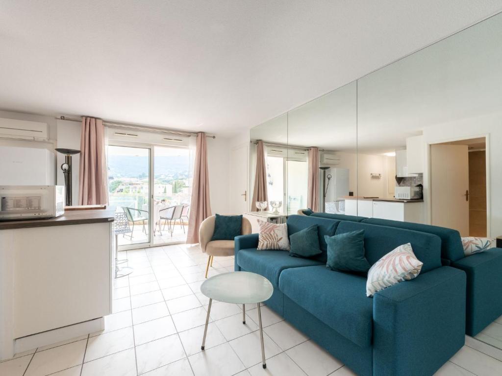 a living room with a blue couch and a kitchen at Apartment Turquoise-10 by Interhome in Cavalaire-sur-Mer
