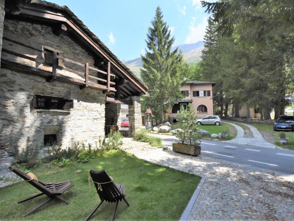 two chairs sitting on the grass next to a building at Chalet Baita Barin by Interhome in Madesimo
