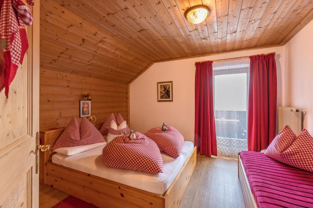 Habitación con 2 camas, cortinas rojas y ventana. en Ciasa Rü, en San Cassiano