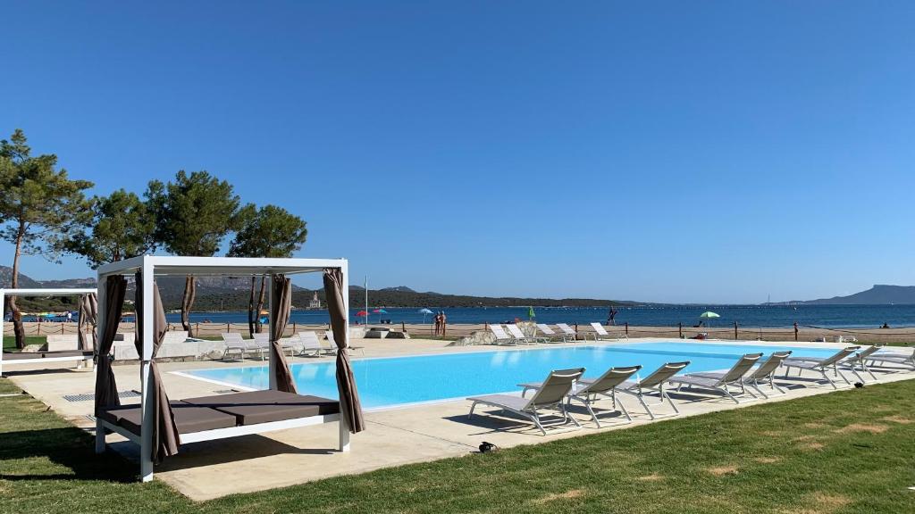 a swimming pool with chairs and a gazebo at Baia del Sole in Olbia