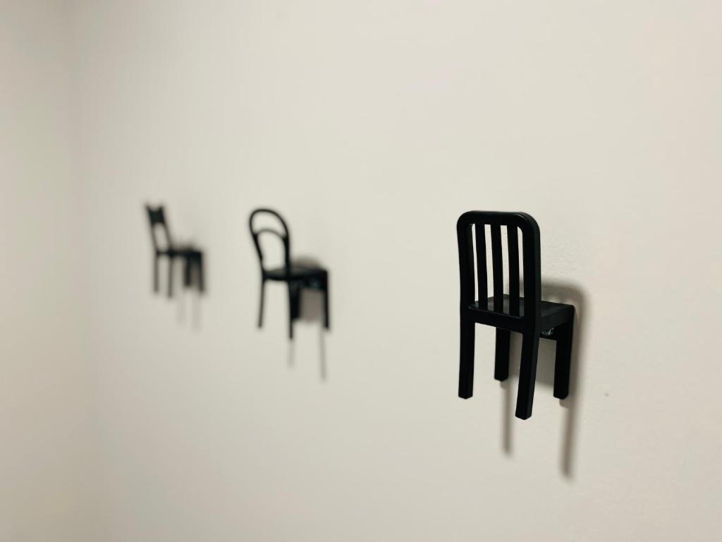 eine Reihe schwarzer Stühle an einer weißen Wand in der Unterkunft Gogalova Apartments in Ljubljana
